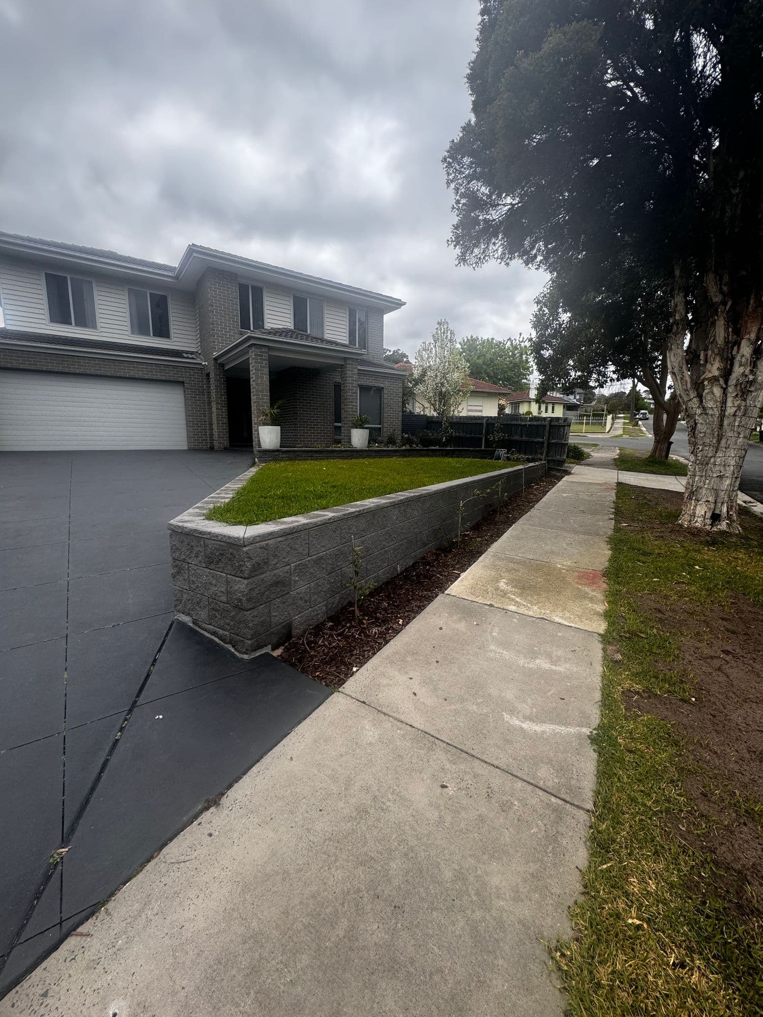 Block retaining wall holding a raised front lawn beside a driveway