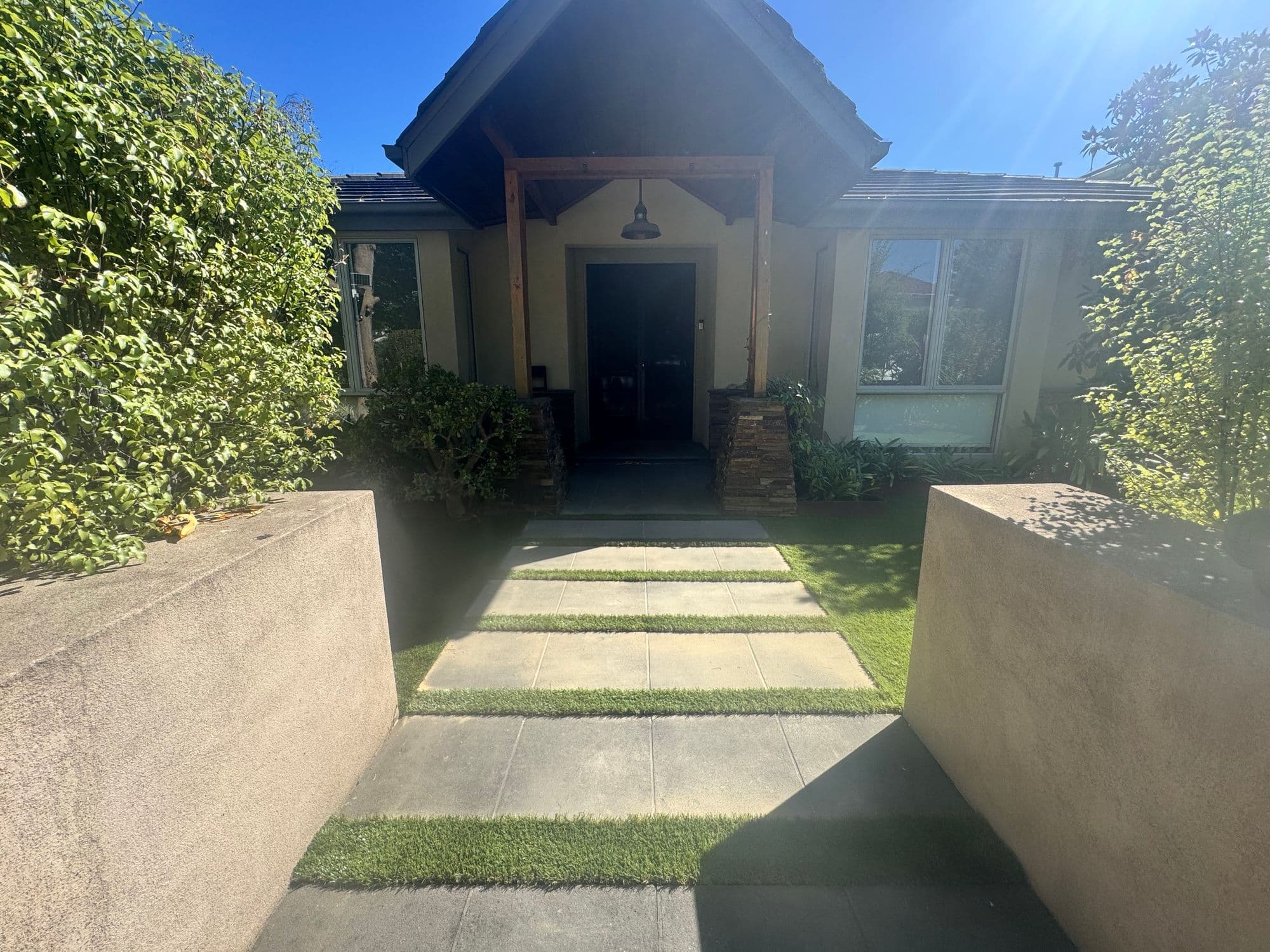Large-format pavers with grass strips leading to a front door