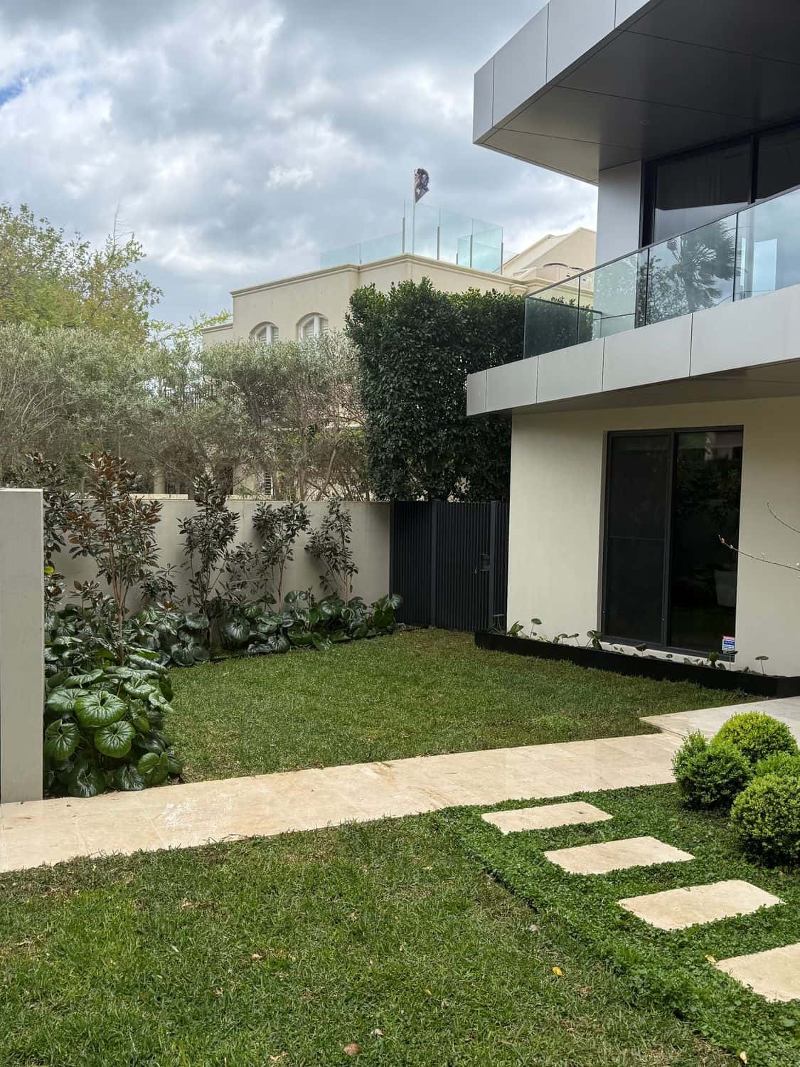Modern front garden in Brighton with Sir Walter buffalo lawns either side of a travertine path and stepping pavers