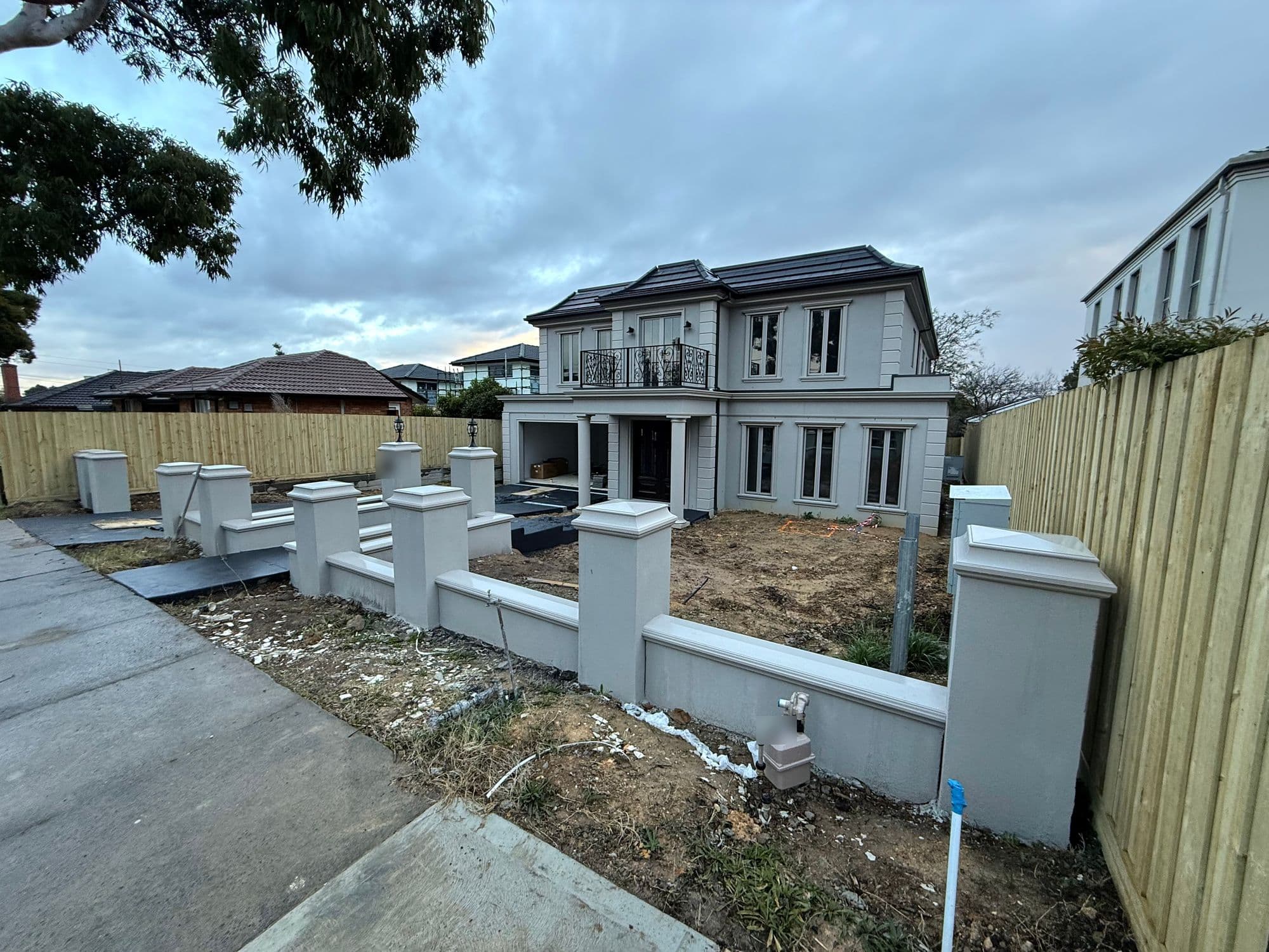 A new double-storey home at handover, with new fences and a front yard of bare clay and builder's leftovers