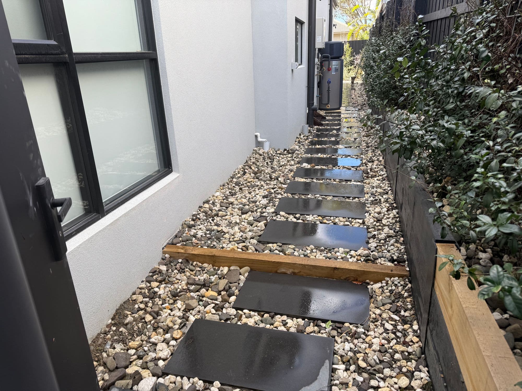 Sawn bluestone stepping slabs set in river pebbles along a side path